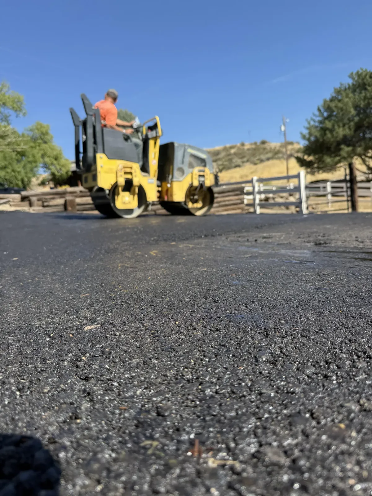 A Superior crew member operates a yellow roller on an asphalt surface.
