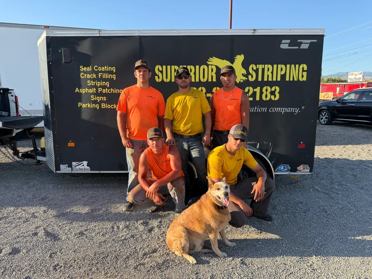 Five Superior Striping crew members and a dog in front of the branded company trailer.